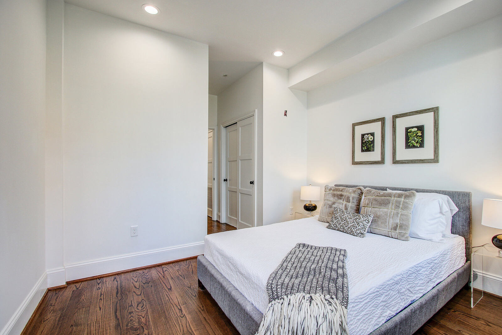 Bright San Diego bedroom with hardwood floors, white walls, a gray upholstered bed, and soft neutral-toned bedding and decor
