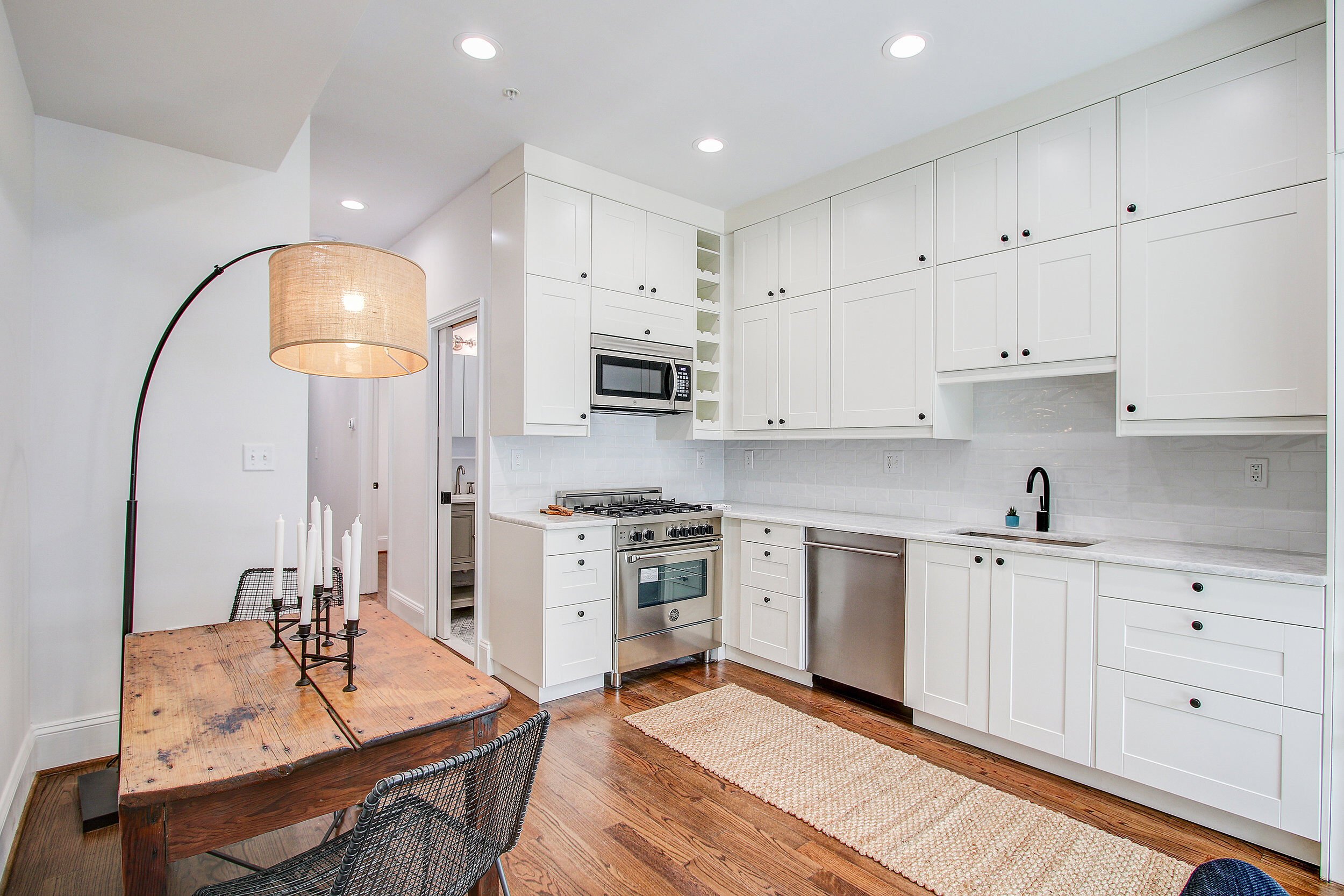 Bright San Diego kitchen with white cabinets, stainless steel appliances, and rustic dining table under a woven pendant lamp
