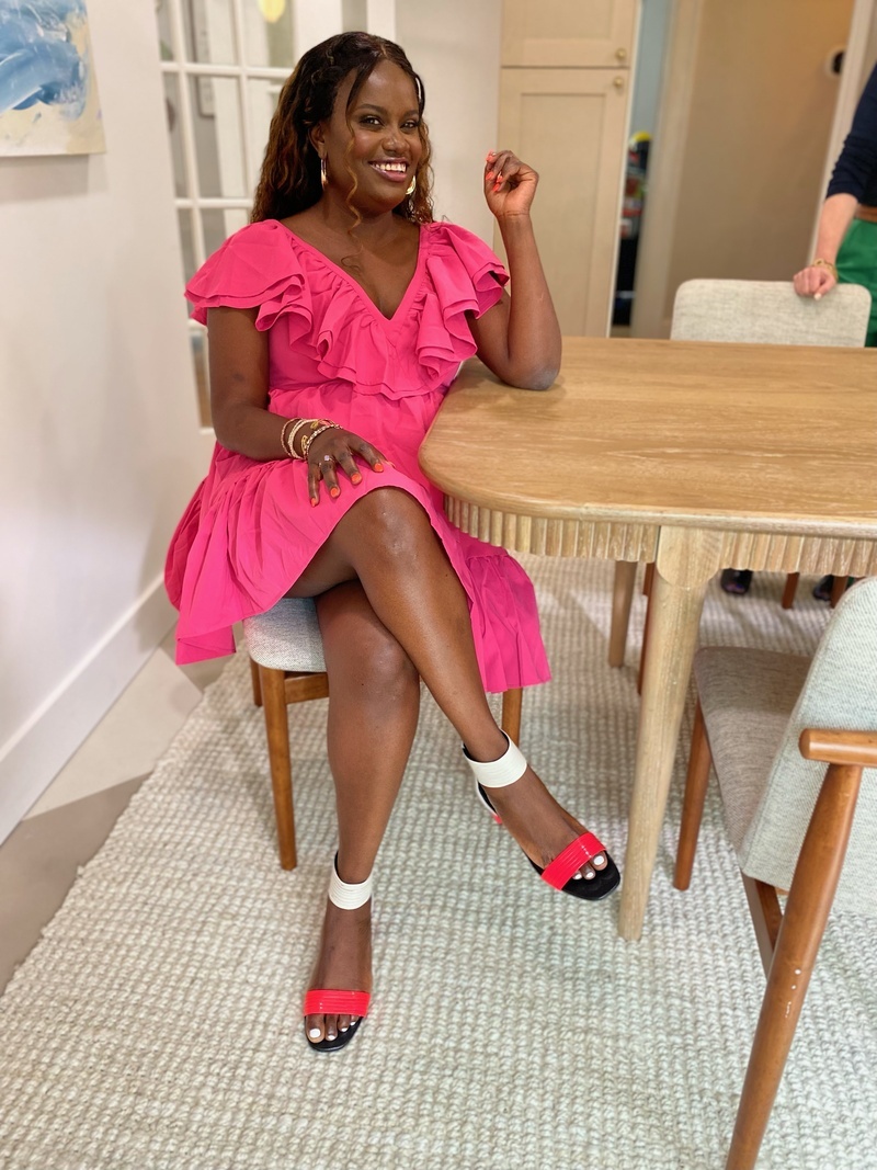 Ati Williams in a pink dress at a kitchen table looking rad